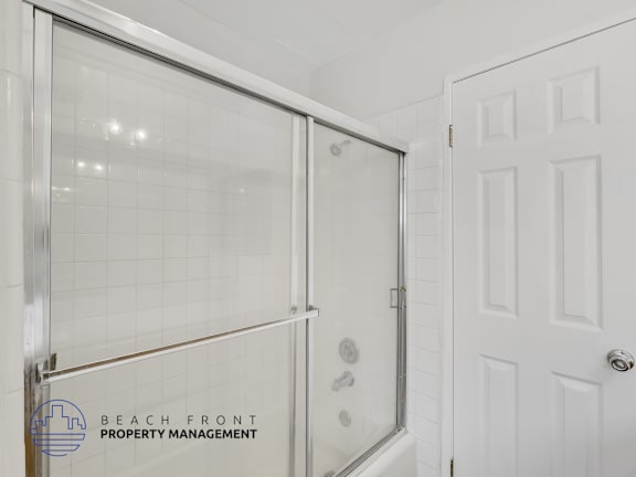 A white door is next to a glass shower stall.
