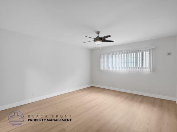A room with a ceiling fan and wooden flooring.