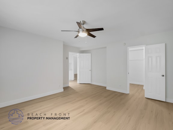 A spacious room with a ceiling fan and wooden flooring.