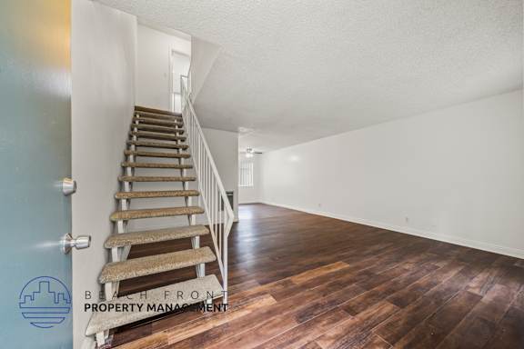 A staircase with a wooden handrail and steps leading to a white door.
