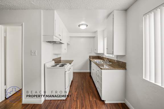 A kitchen with white cabinets and a wooden floor.