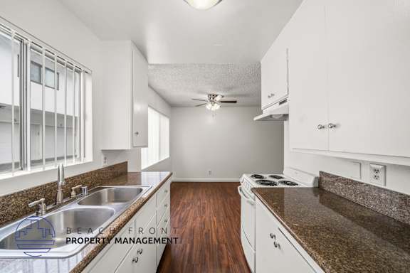 A kitchen with white cabinets and a brown countertop.