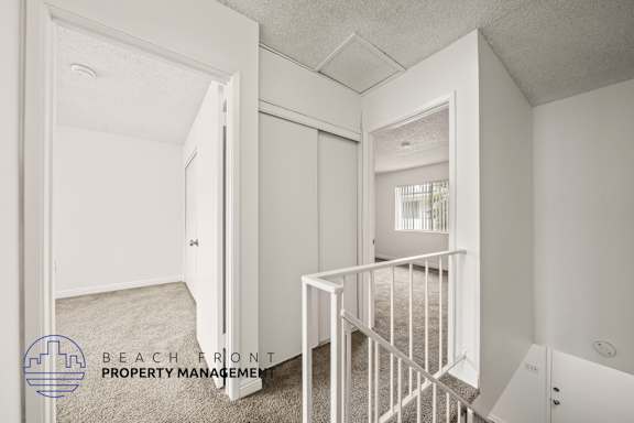 A white room with a carpeted floor and a white railing.