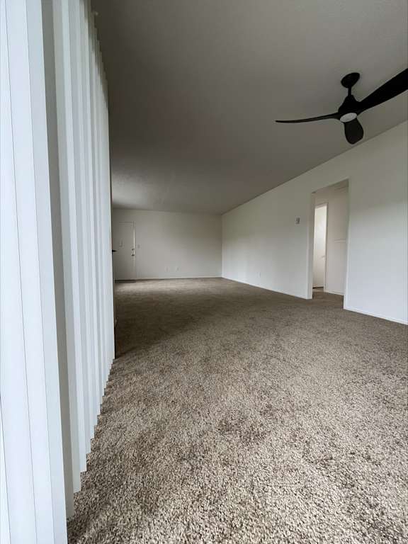 an empty living room with carpet and a ceiling fan