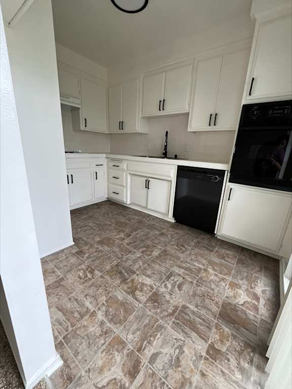 an empty kitchen with white cabinets and black appliances