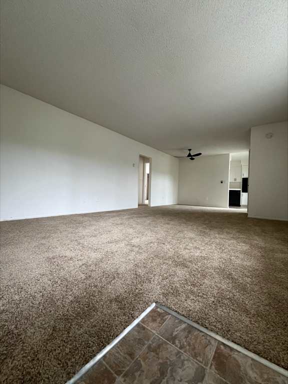 an empty living room with carpet and a ceiling fan