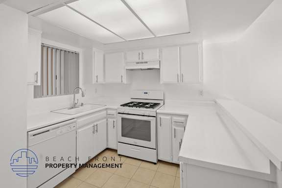 A kitchen with white appliances and cabinets.