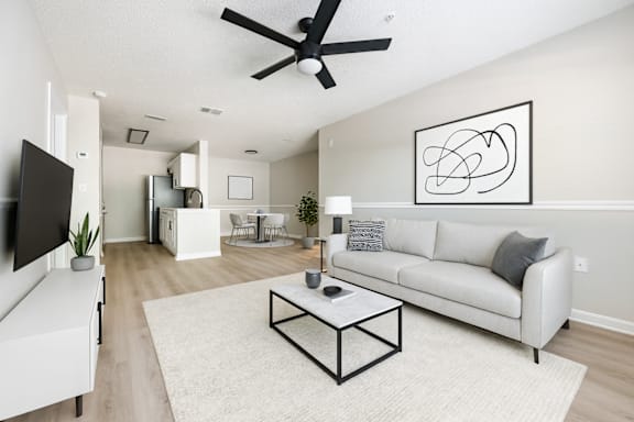 A living room with a white couch, a coffee table, and a ceiling fan.