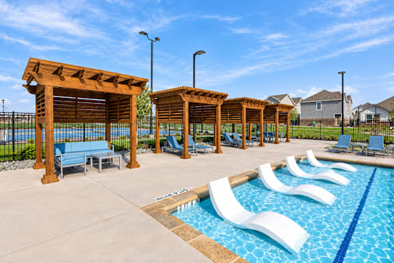 A pool area with sun loungers and a wooden pergola.