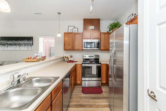A kitchen with a refrigerator, sink, and microwave.