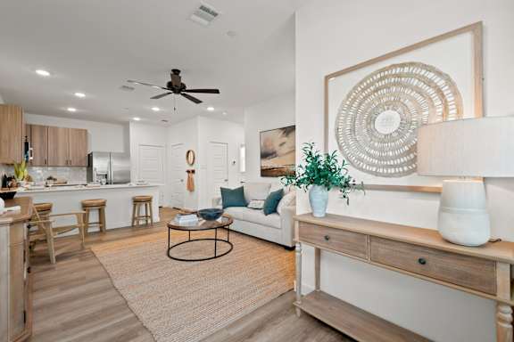 A living room with a white couch, a coffee table, and a large decorative piece on the wall.