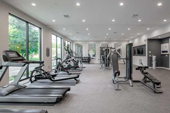 A spacious gym with treadmills, exercise bikes, and weight machines.