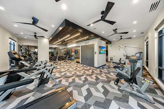 A spacious gym with a variety of equipment and a patterned floor.