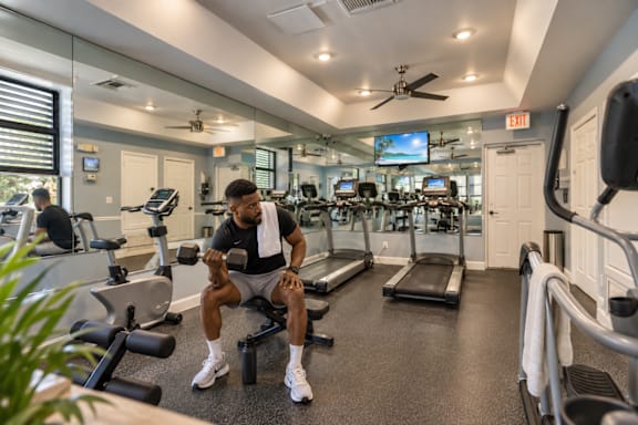 A man is working out in a gym with a variety of equipment.