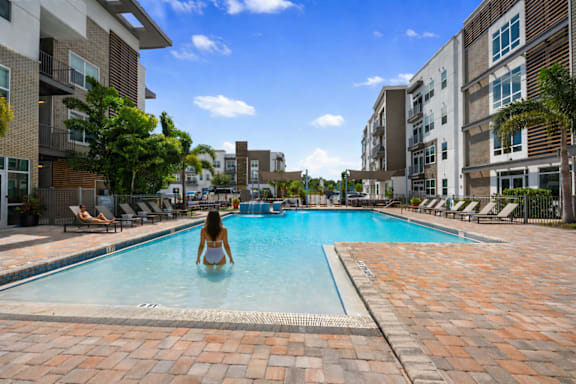 A woman is sitting in a pool surrounded by buildings.