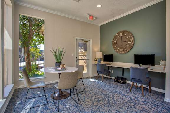 A room with a table, chairs, and a clock on the wall.