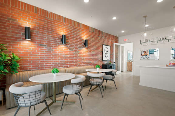 A room with a white table and chairs with a red brick wall.