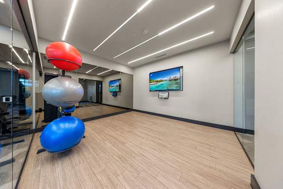 A room with a blue exercise ball and a red exercise ball on a wooden floor.