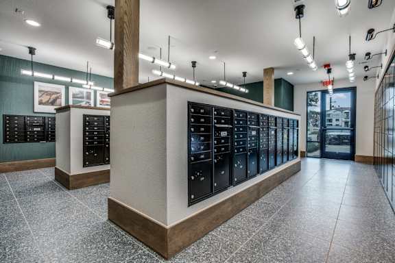 A row of black vending machines are lined up in a room with a tiled floor.