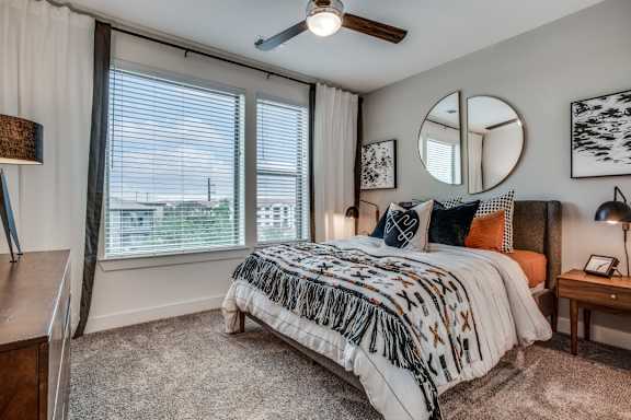 A bedroom with a large bed and a ceiling fan.