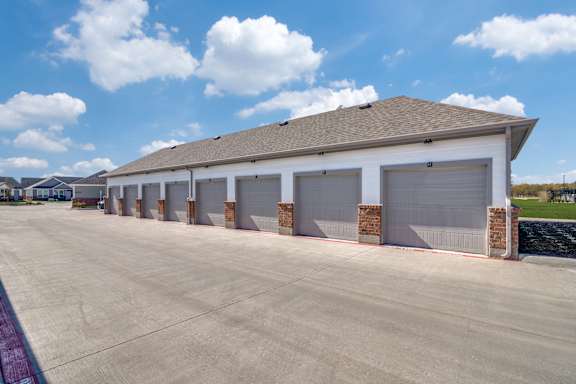 A large building with a grey roof and white walls has a row of garage doors.