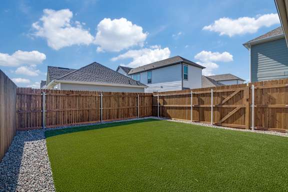 A backyard with a green lawn and a wooden fence.