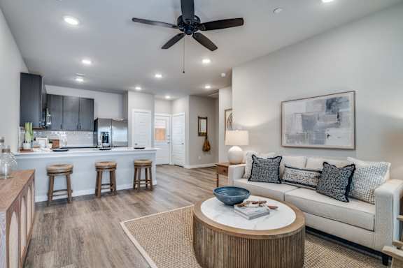 A modern living room with a ceiling fan and a white couch.