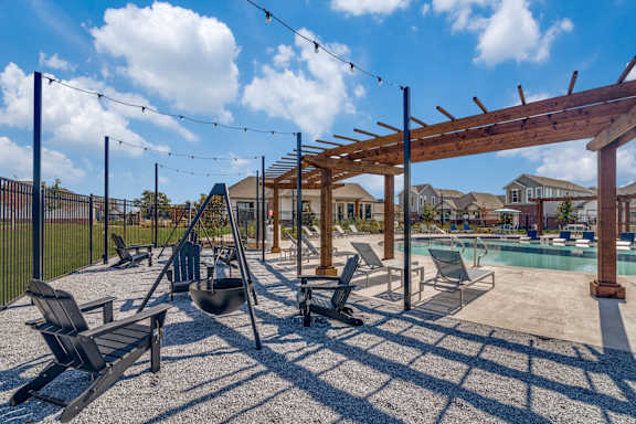 A sunny day at the pool with a wooden pergola and lounge chairs.