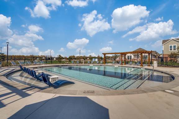 A large outdoor swimming pool with a slide and a gazebo in the background.