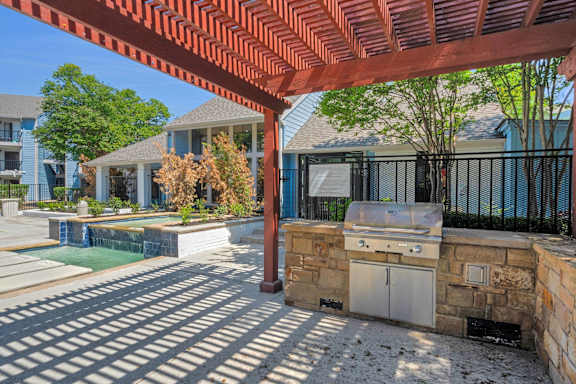 A patio with a grill and a pool.