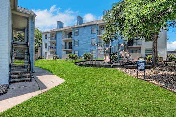 A blue apartment building with a green lawn in front.