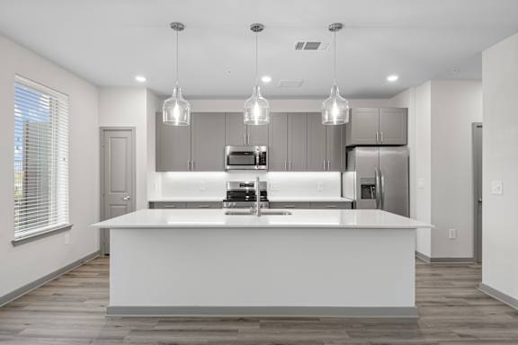 A modern kitchen with a large island and pendant lights.