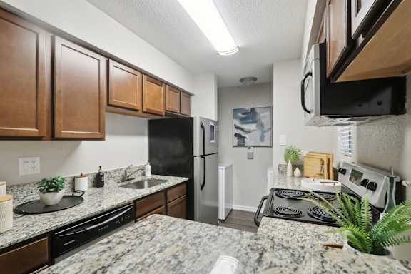 A kitchen with granite countertops and a black refrigerator.
