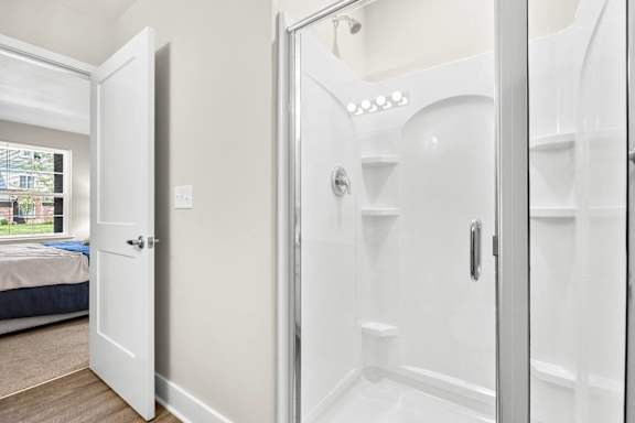 a bathroom with a shower and a bed in a room