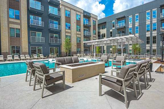 A poolside area with chairs and a hot tub in front of a building.