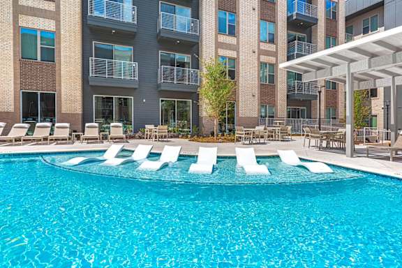 A pool with chairs around it in front of a building.