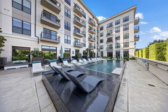 A modern apartment complex with a pool in the foreground.