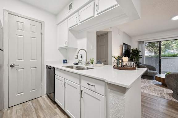 A white kitchen with a sink and a window.