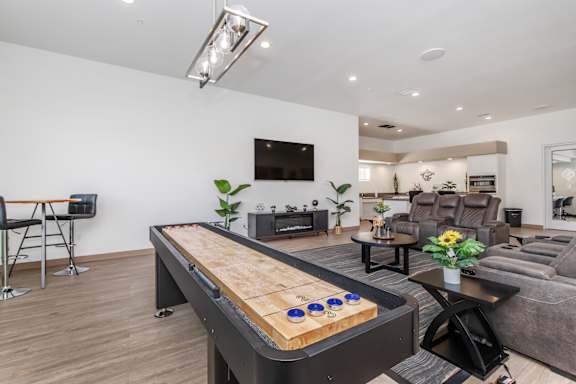 A shiny pool table in the middle of a room with a tv and a couch.