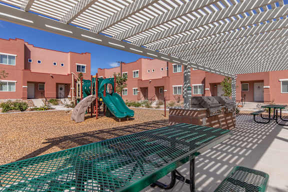 A playground with a green slide and a green bench.