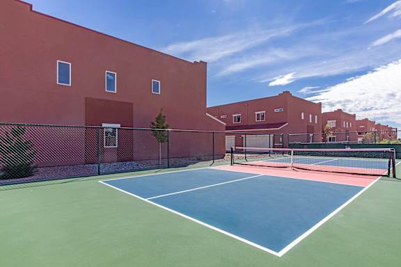 A tennis court is surrounded by a red wall.