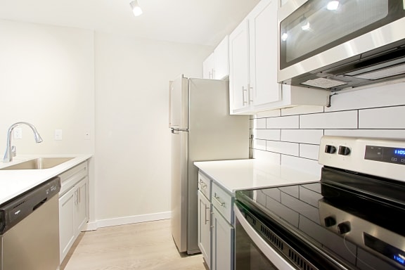 a kitchen with white cabinets and stainless steel appliances