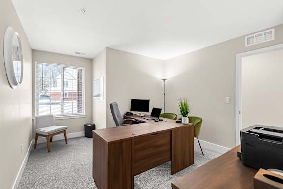 an office with a wooden desk and a large window