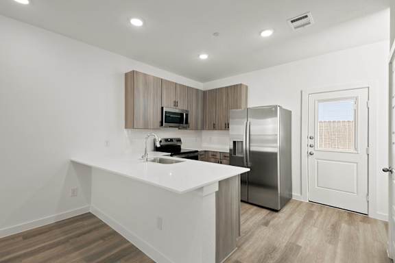 A modern kitchen with a white countertop and stainless steel appliances.