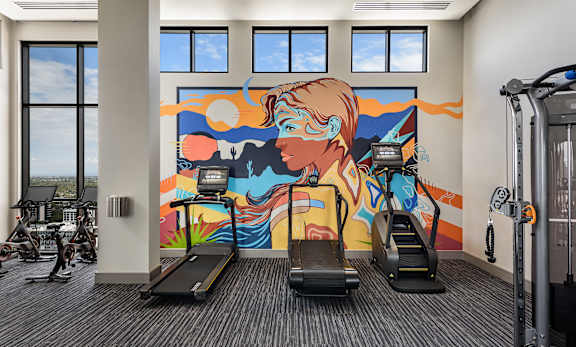 A gym with treadmills and a colorful mural on the wall.