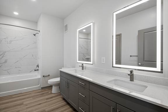 A bathroom with a marble tub surround, a white sink, and a large mirror.