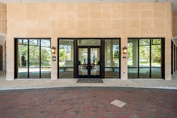 A building with a tan wall and black doors.