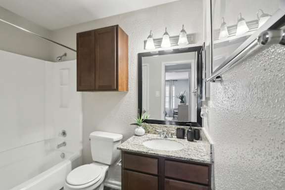 A bathroom with a white toilet, a sink, and a mirror.