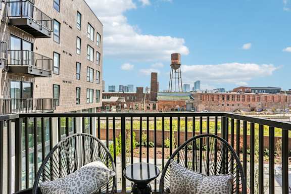 Two chairs with leopard print cushions are on a balcony overlooking a cityscape.