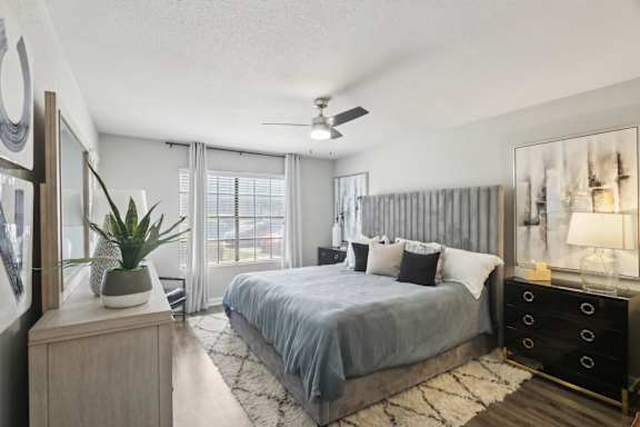 A bedroom with a bed, dresser, and ceiling fan.